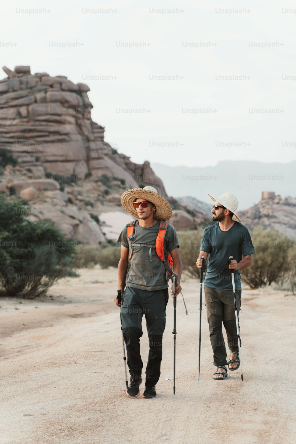 a couple of men walking across a dirt road