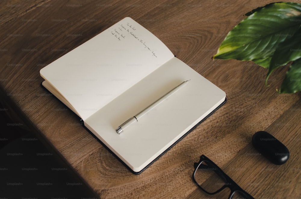 an open notebook on a desk next to a pair of glasses