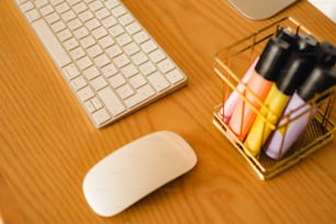 a desk with a computer keyboard, mouse and pens