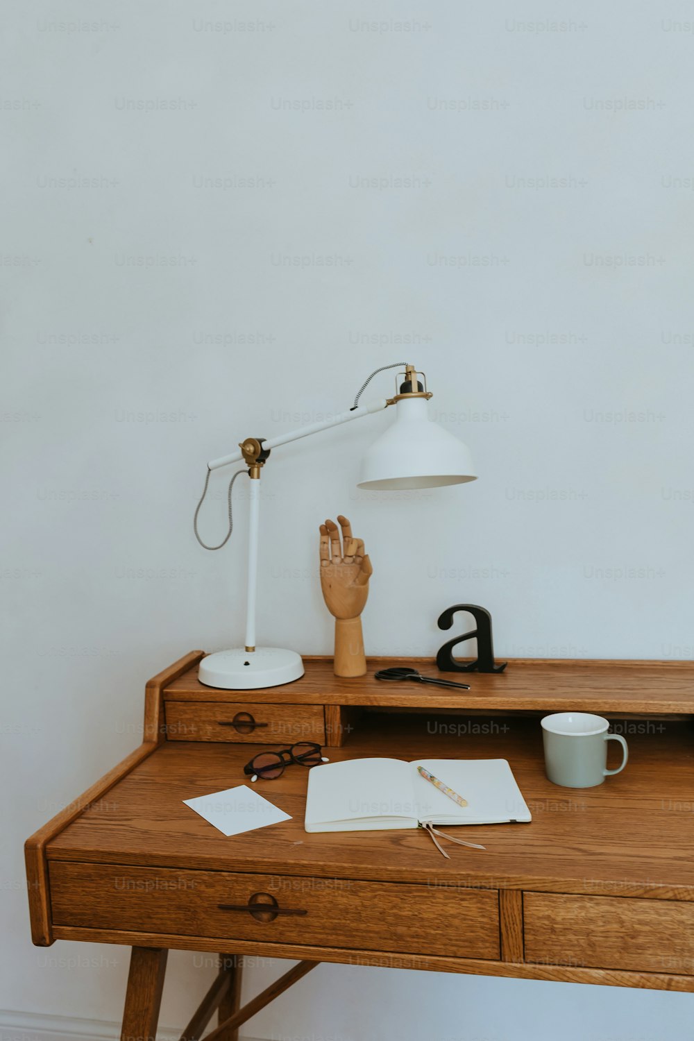 a wooden desk topped with a lamp and a book