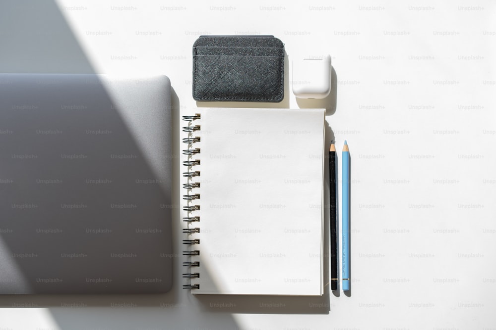 um bloco de notas, caneta e um laptop em uma mesa