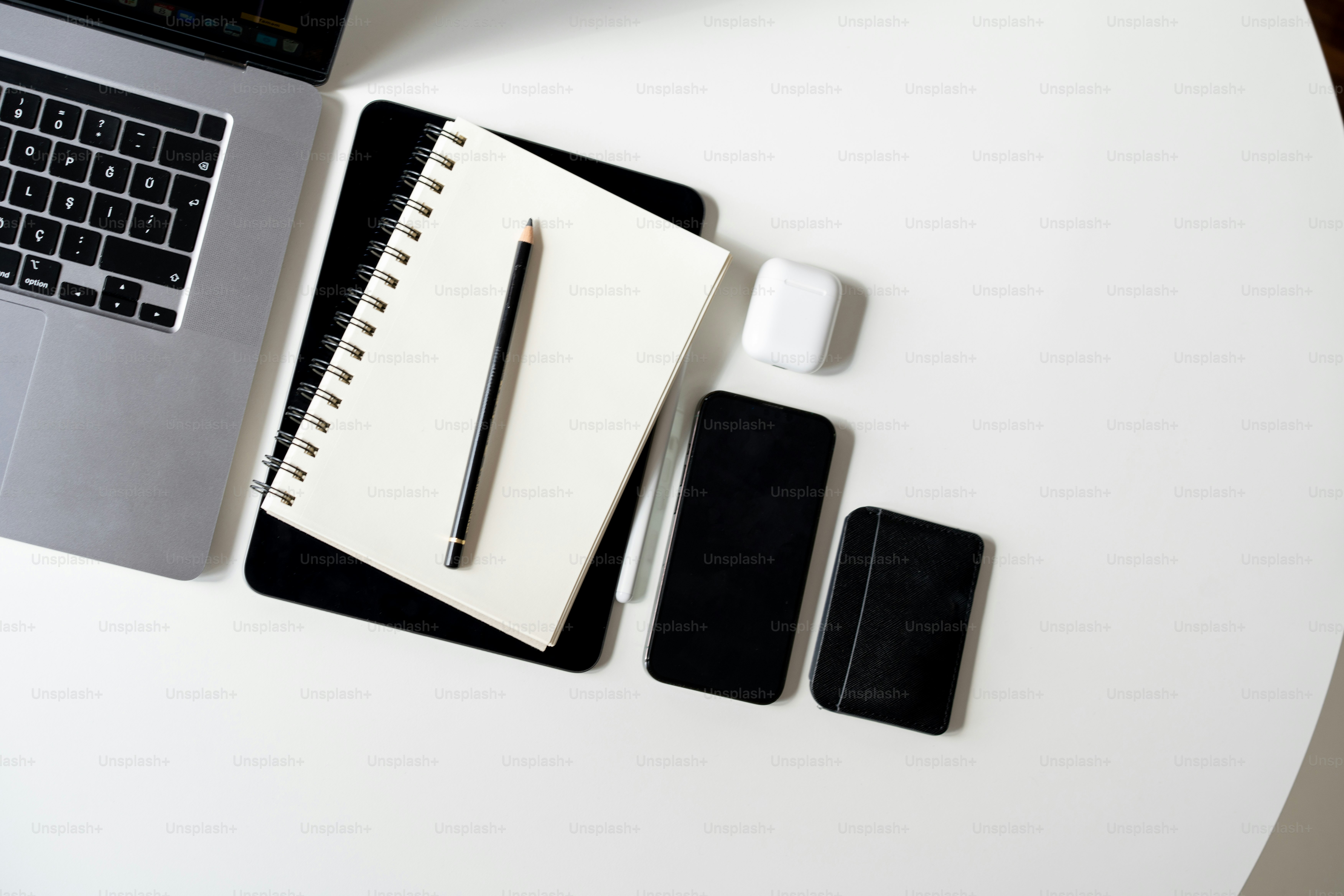 a desk with a laptop, notepad, and pen