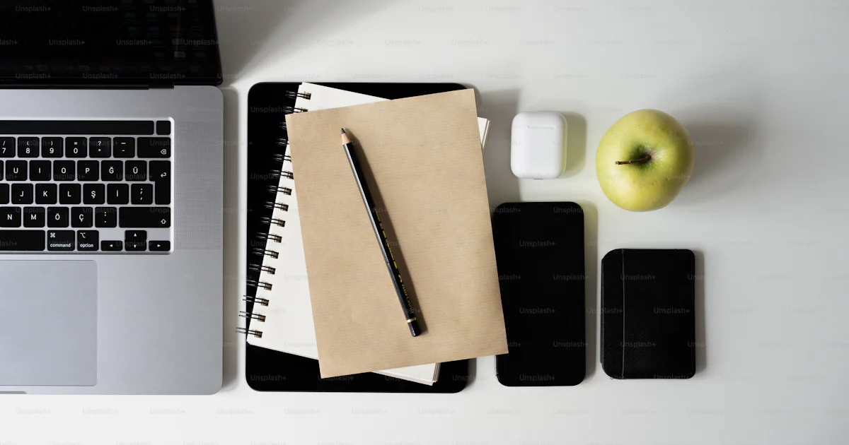 A notebook, pen, and apple sitting on a desk next to a laptop photo ...