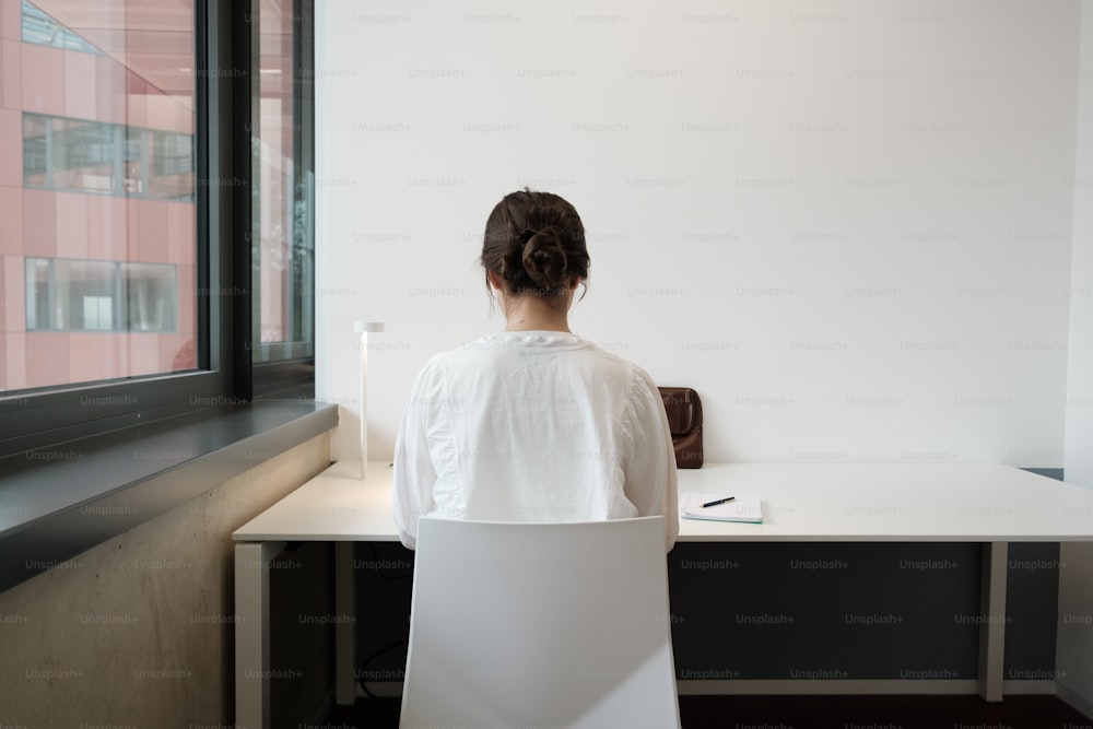 Una donna seduta a una scrivania che guarda fuori da una finestra