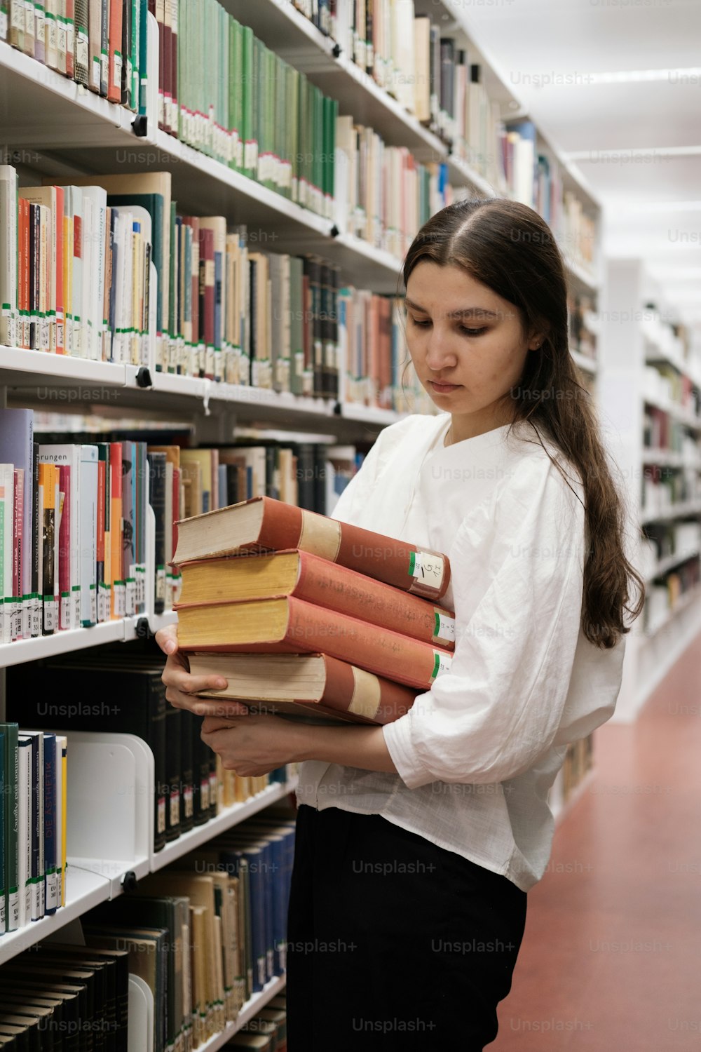 a woman holding a stack of books in a library