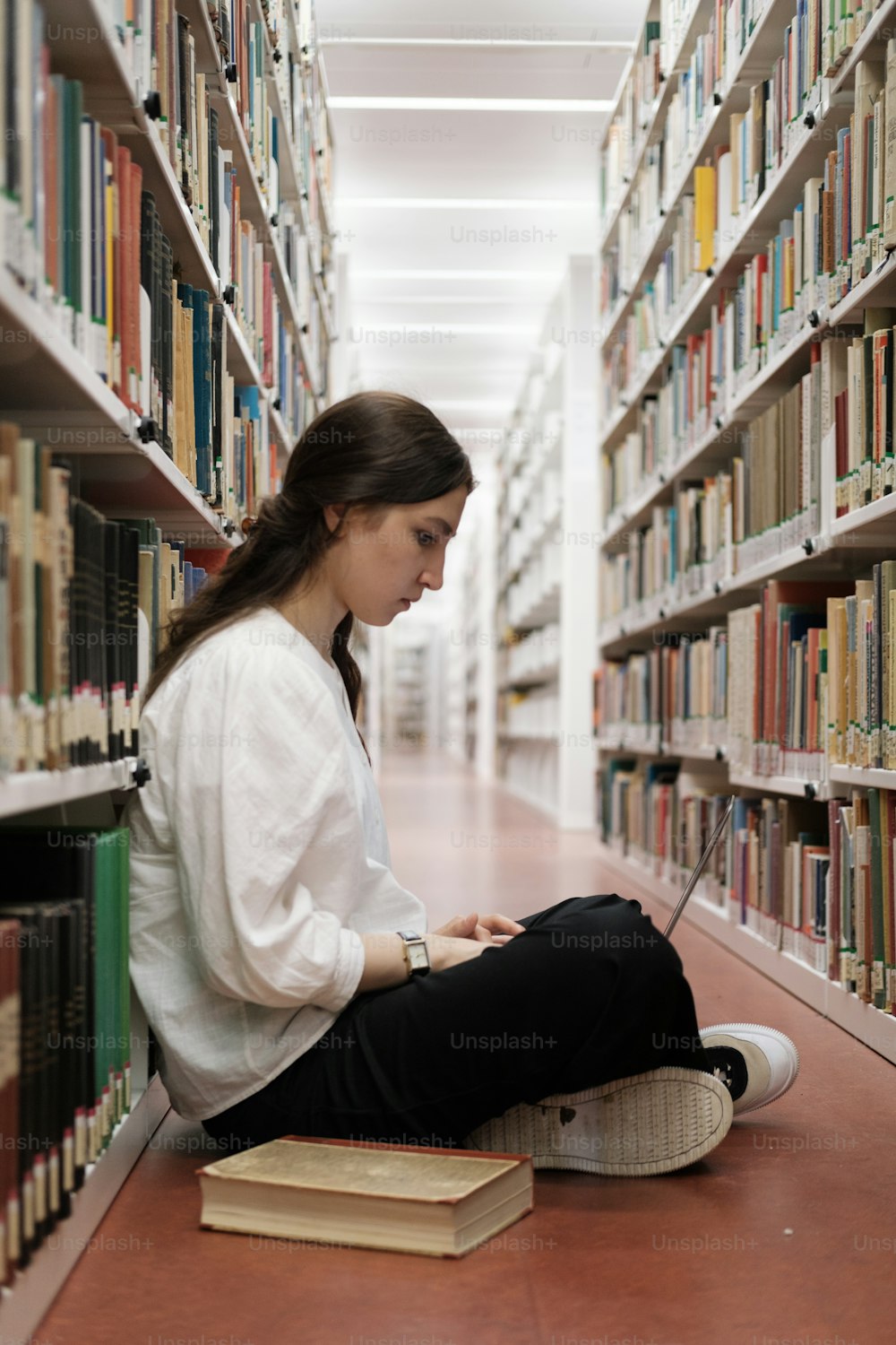 Una donna seduta sul pavimento in una biblioteca