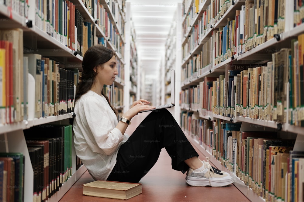 Una mujer está sentada en el suelo en una biblioteca