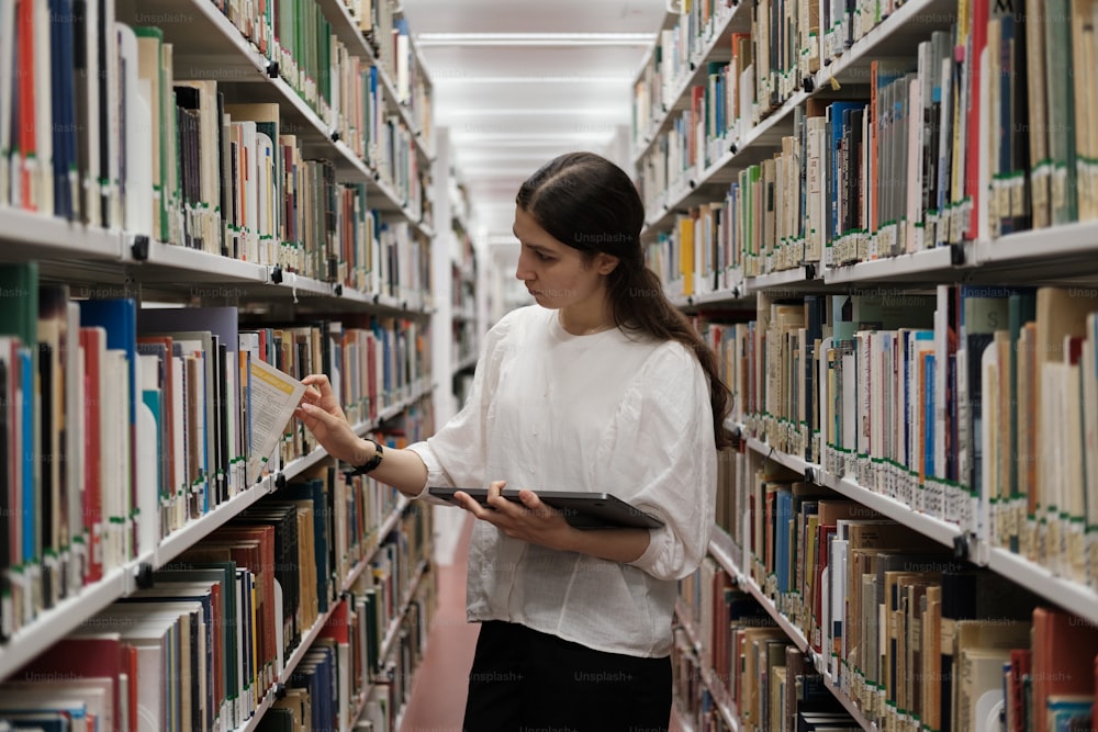 uma mulher em pé em uma biblioteca segurando um livro