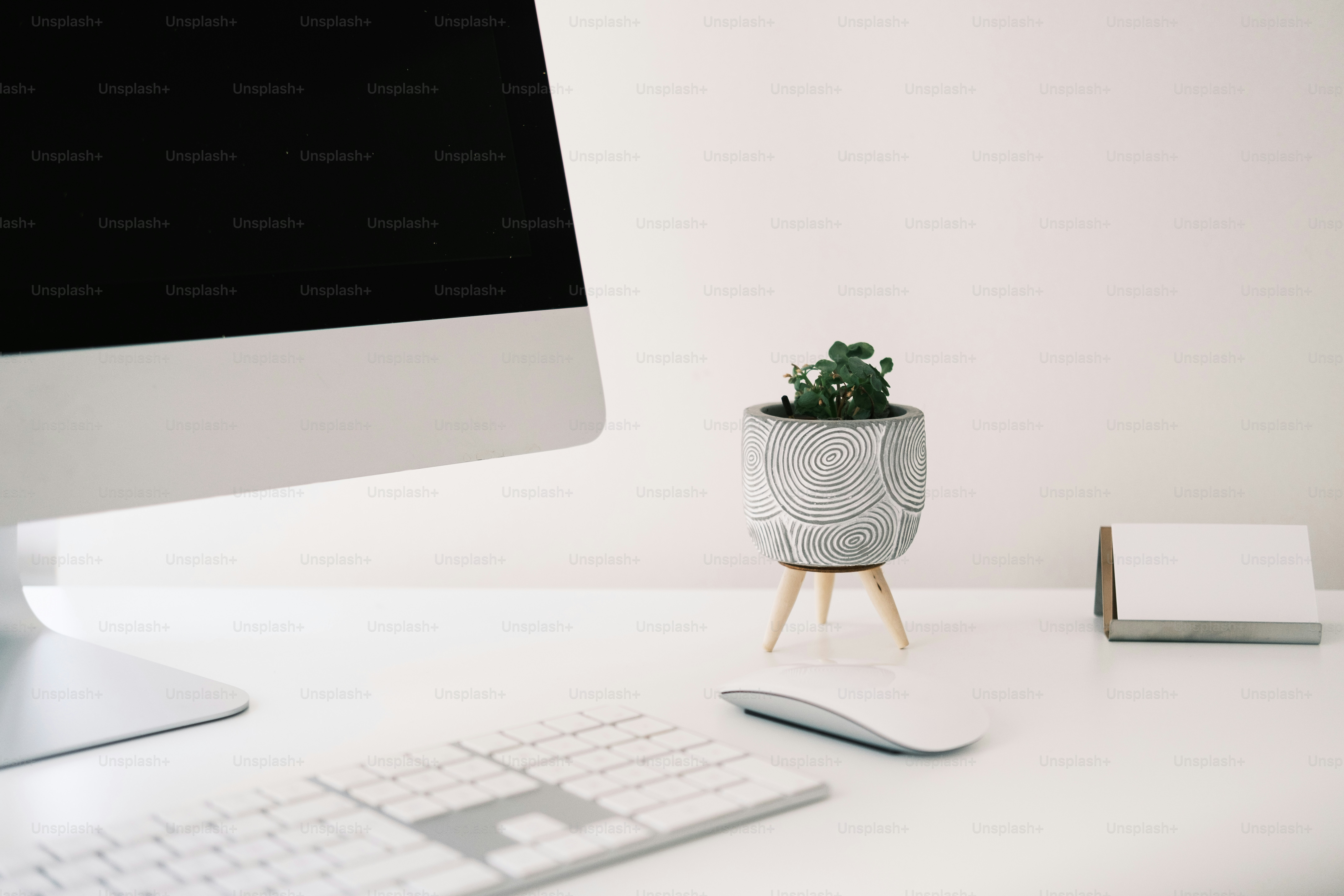 a desk with a computer, keyboard and a plant