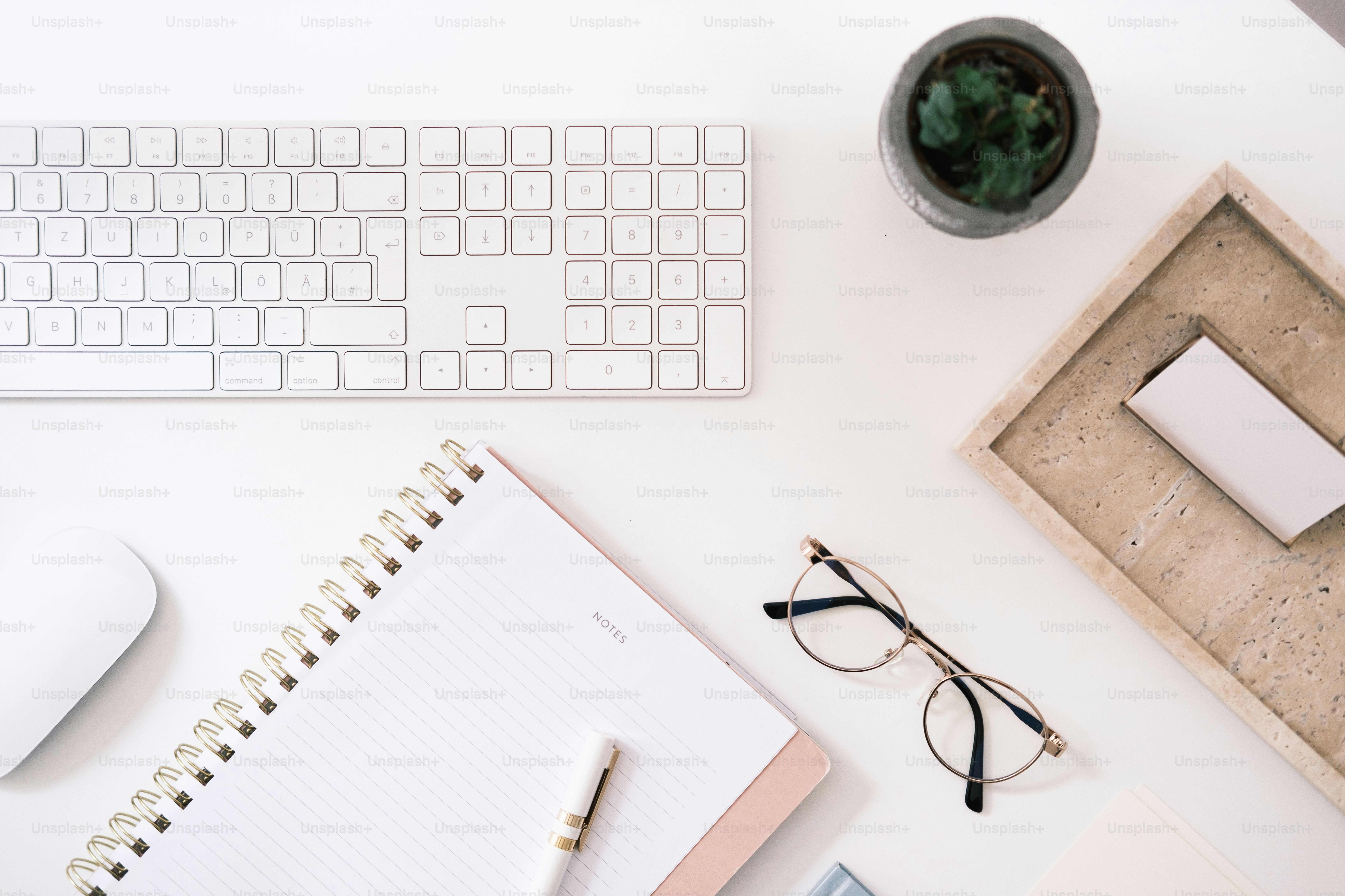 A desk with a keyboard, mouse, glasses and a notepad photo Notes