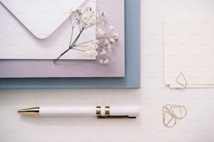 um bloco de notas, uma caneta e uma flor sobre uma mesa