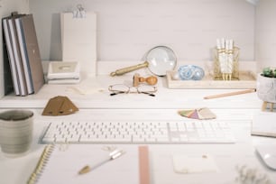 a desk with a keyboard, mouse, glasses, and other items