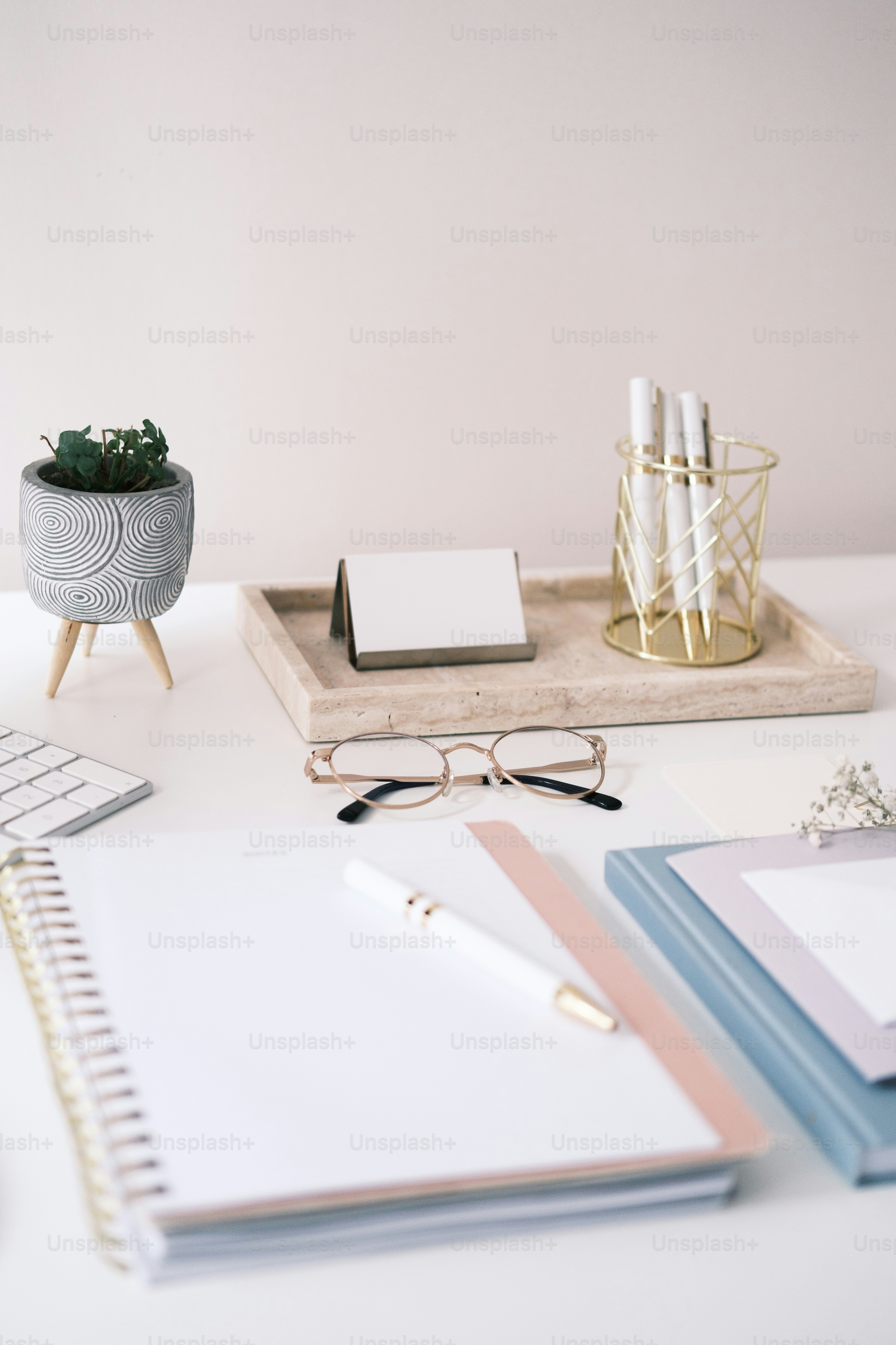 a desk with a notebook, pen and glasses