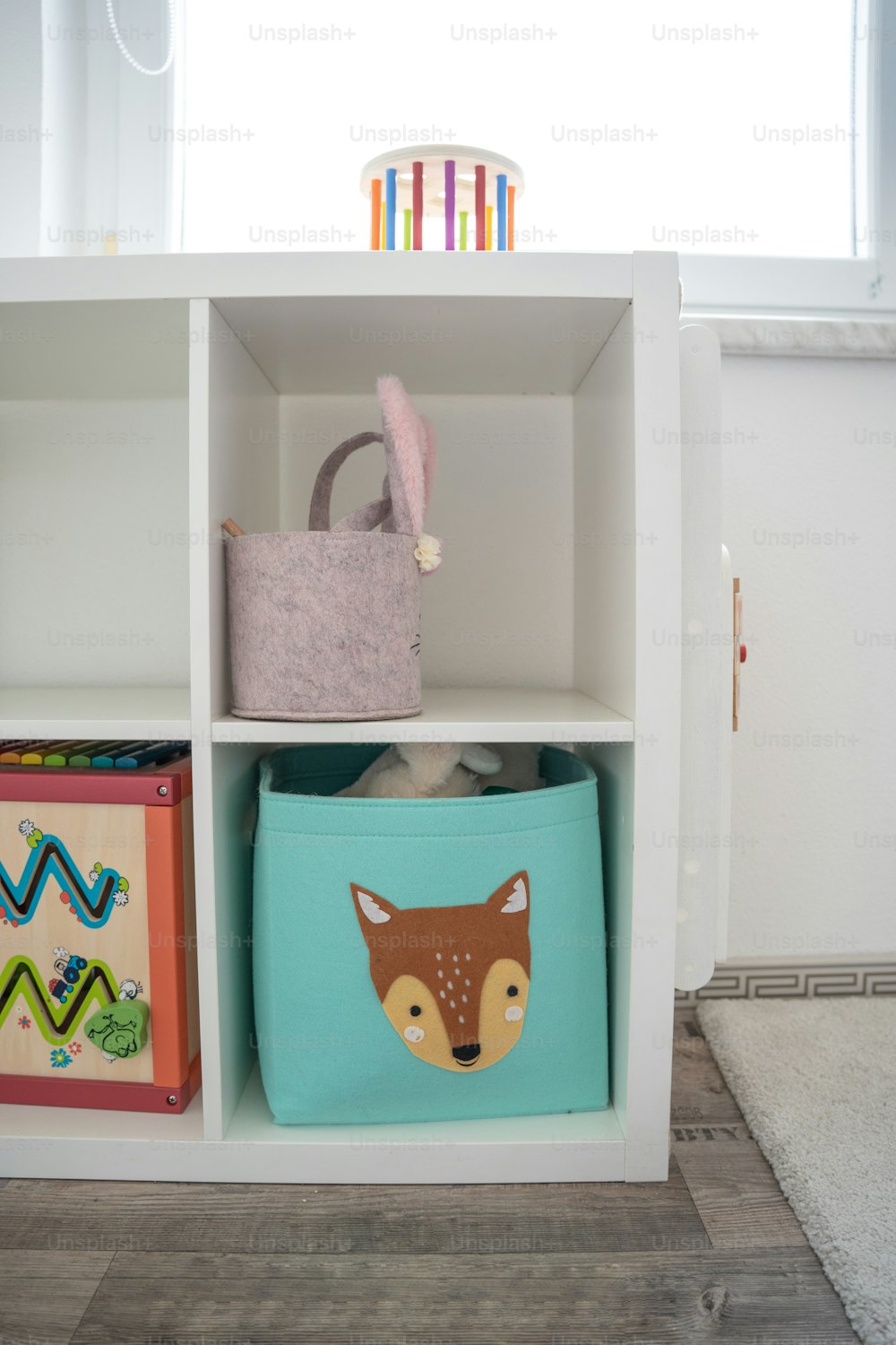 a white book shelf filled with toys and a basket