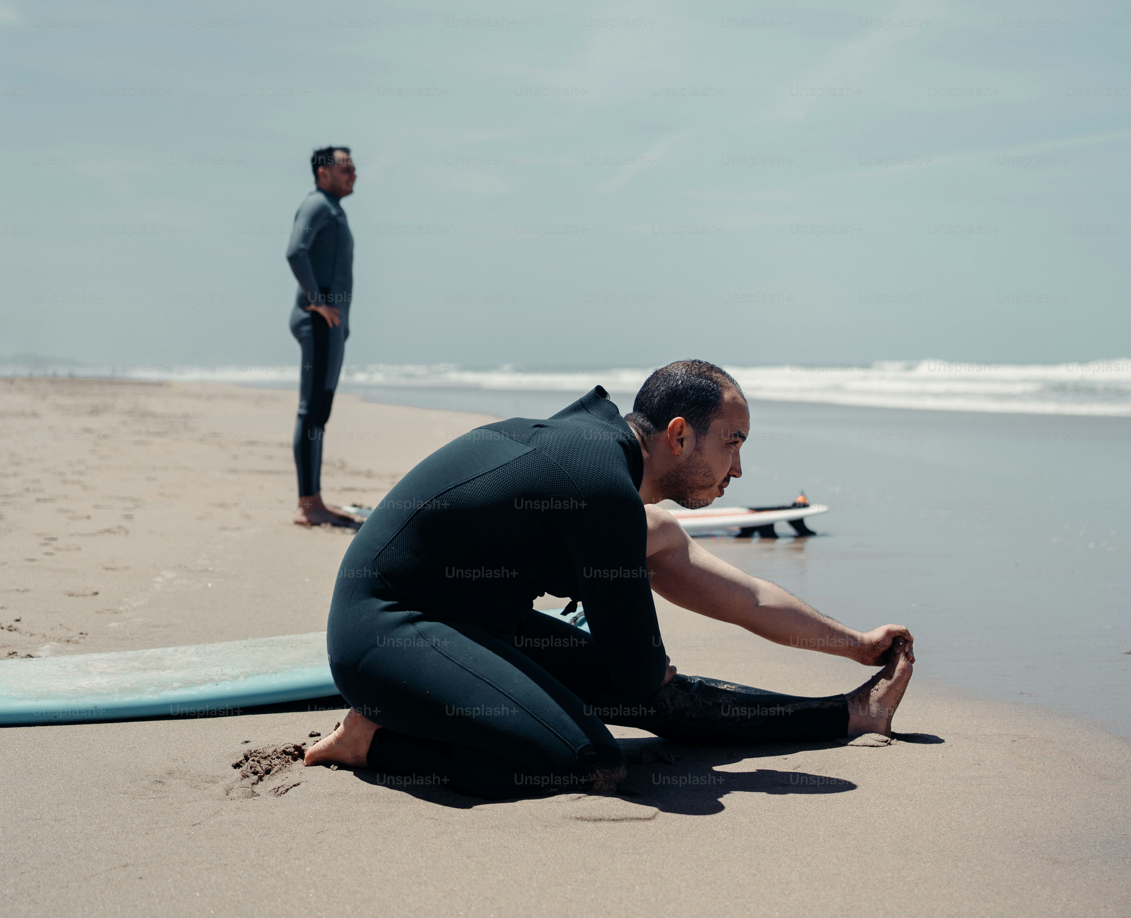 a man sitting on the beach next to a surfboard