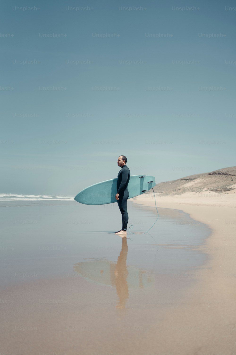 a man standing on a beach holding a surfboard