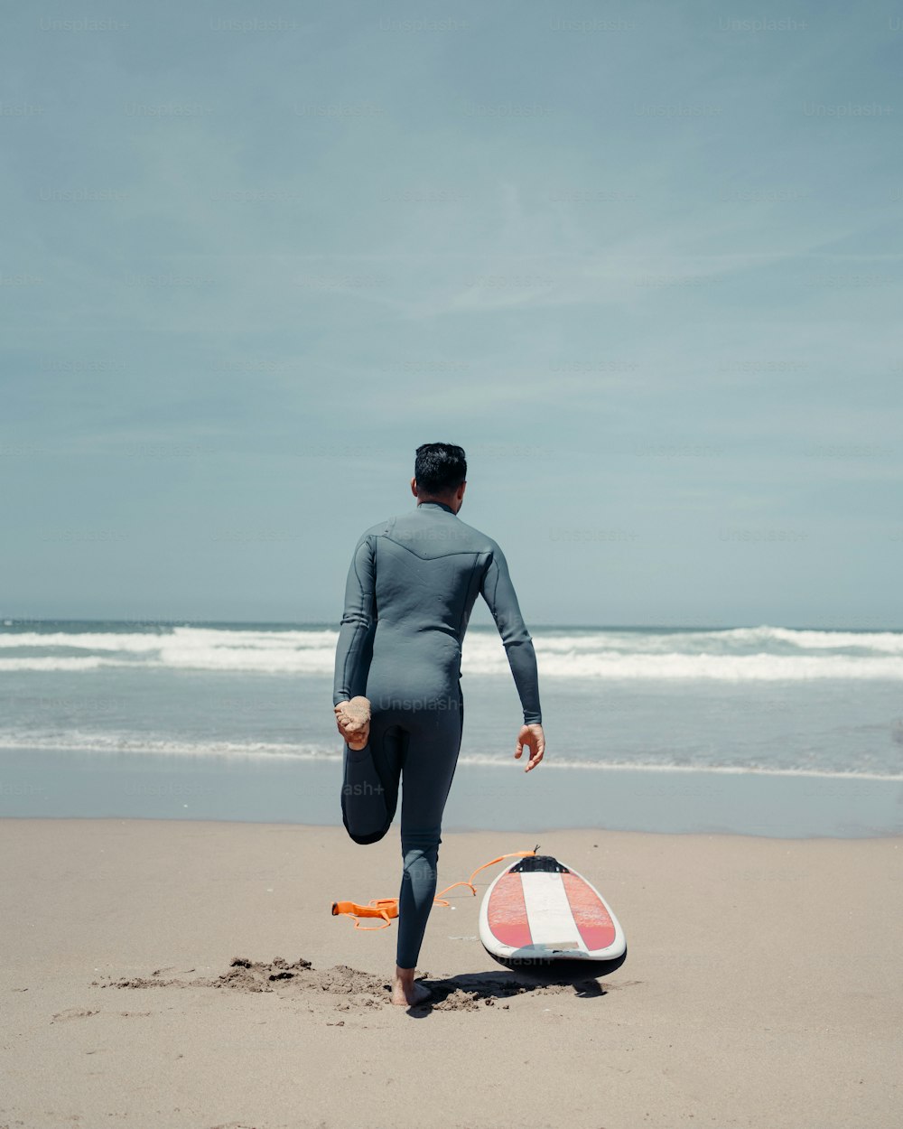 a man in a wet suit running on the beach