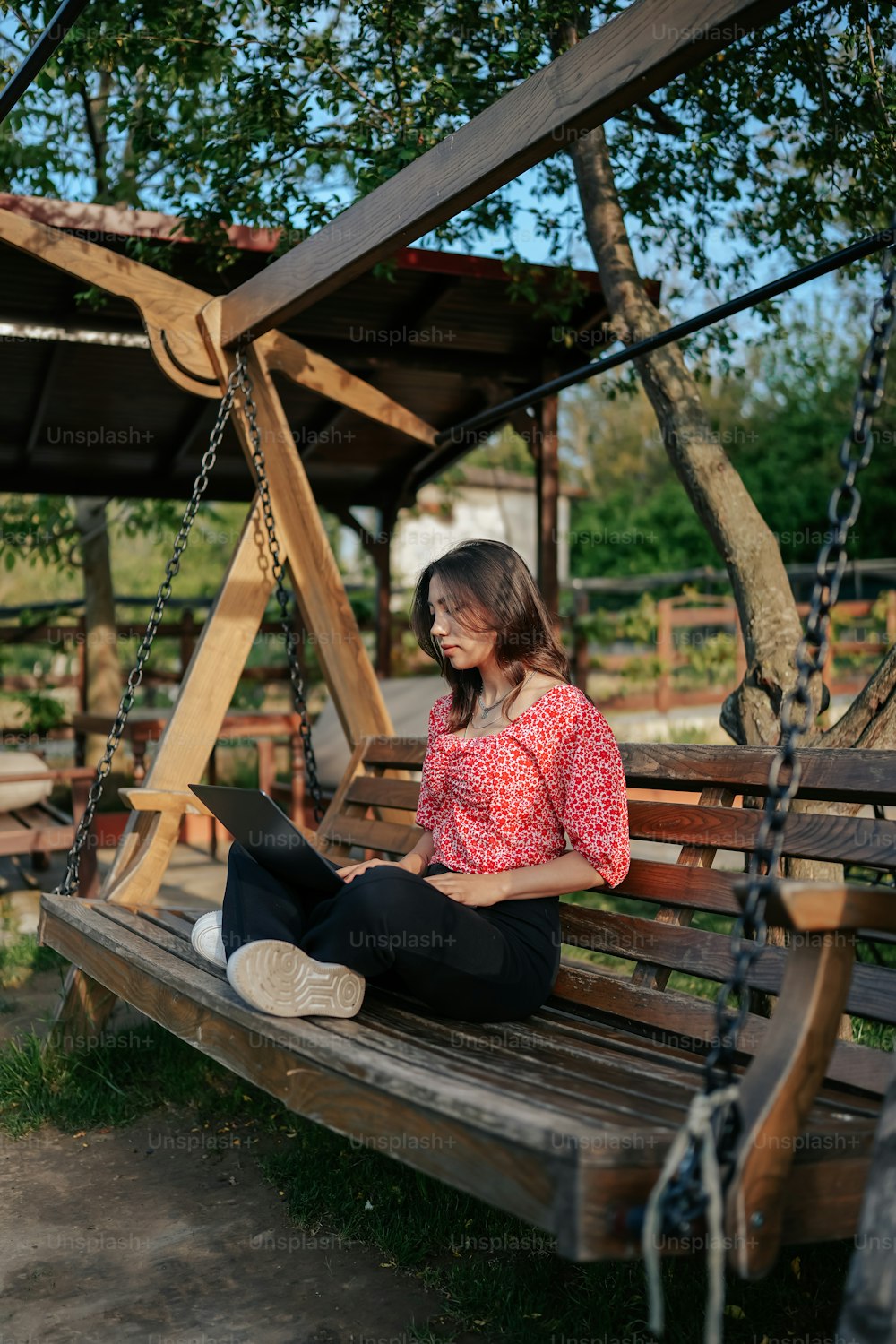 a woman sitting on a swing using a laptop