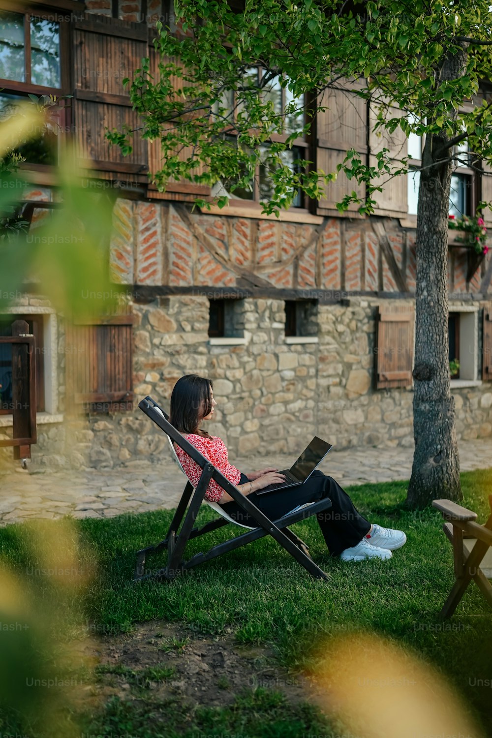 uma mulher sentada em uma cadeira de gramado em frente a um prédio