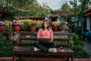 Eine Frau, die mit einem Laptop auf einer Bank sitzt