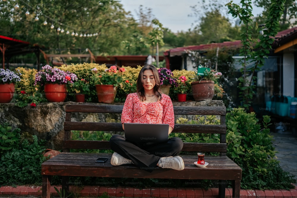 ノートパソコンを持ってベンチに座っている女性