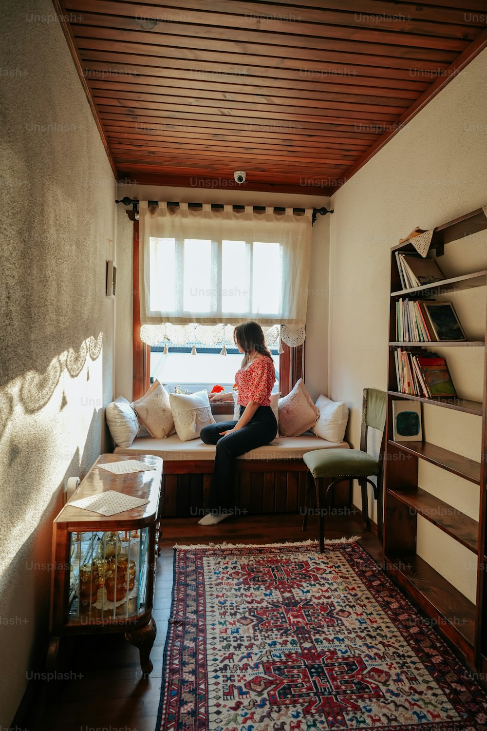 a woman sitting on a window seat in a living room