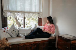 a woman sitting on a window sill looking out the window