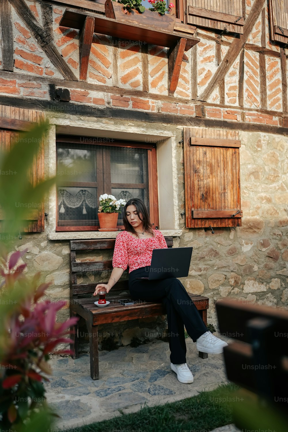 a woman sitting on a bench with a laptop
