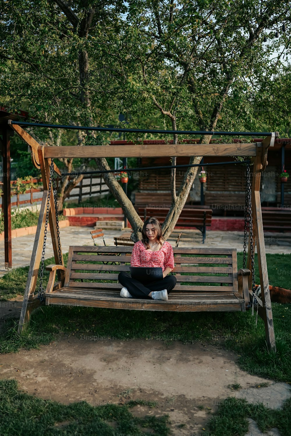 a woman sitting on a swing in a park