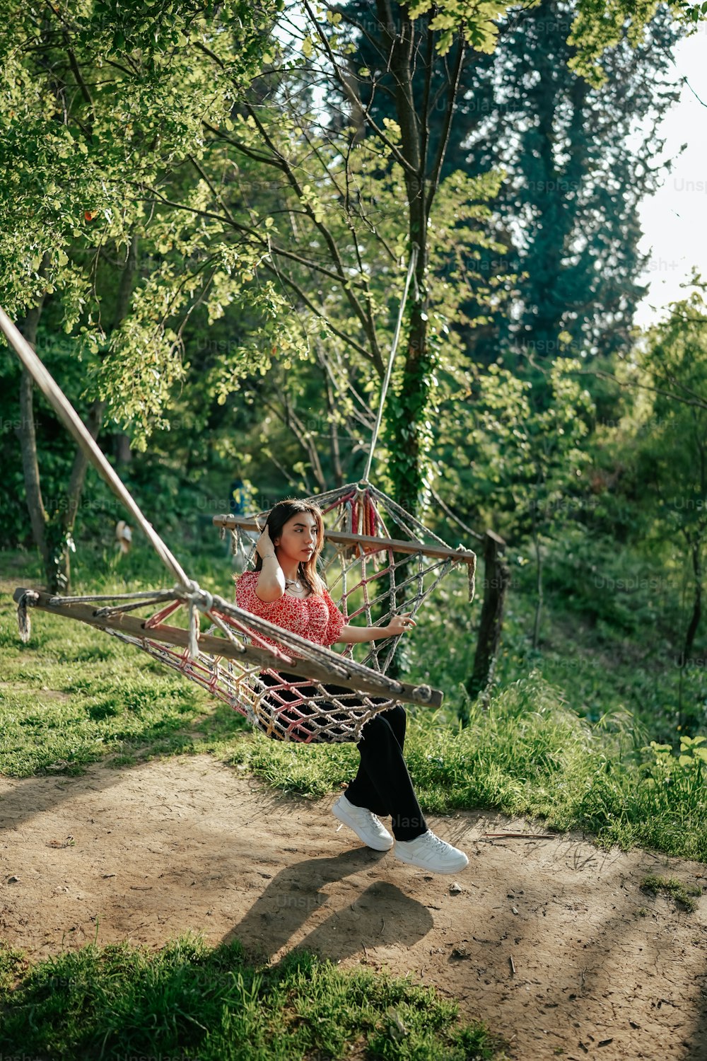 a woman sitting in a hammock in a park