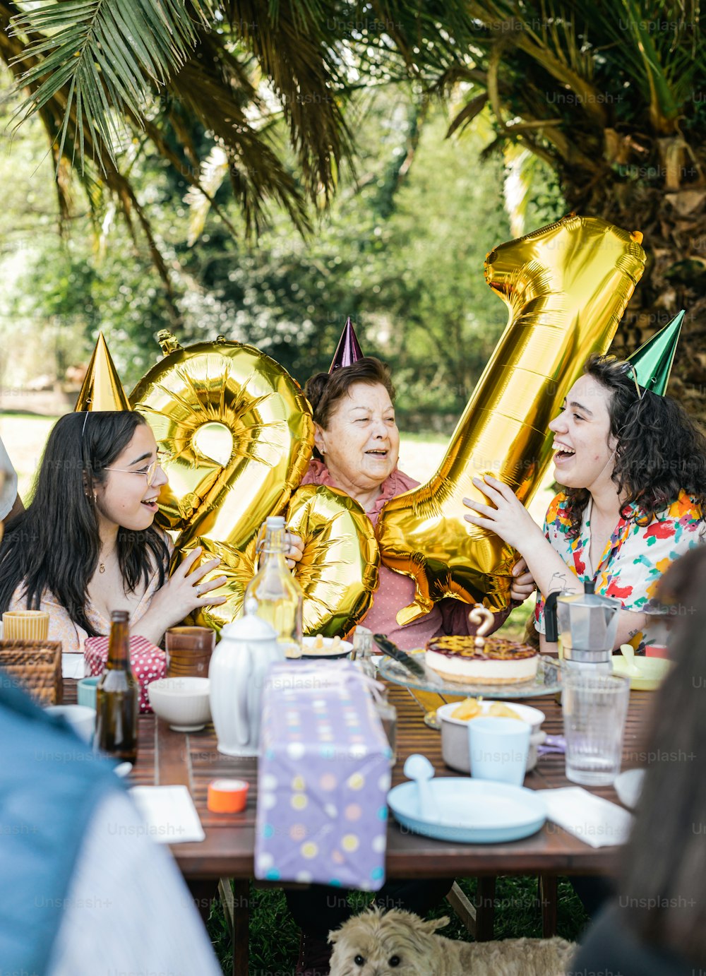 a group of people sitting at a table with gold balloons