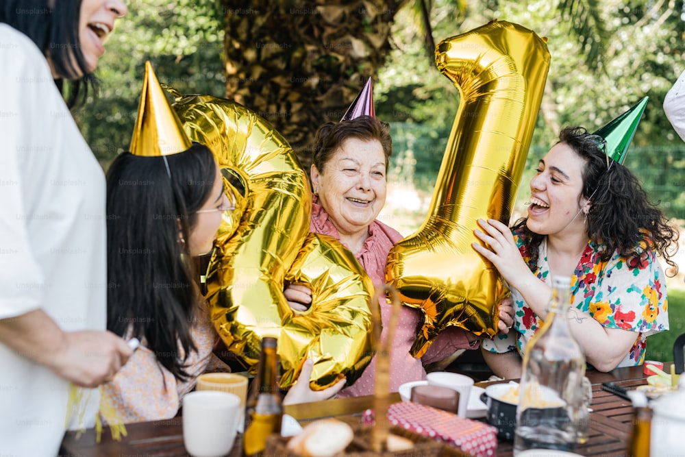 a group of people sitting around a table with gold balloons