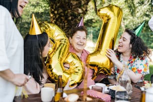 Un grupo de personas sentadas alrededor de una mesa con globos dorados