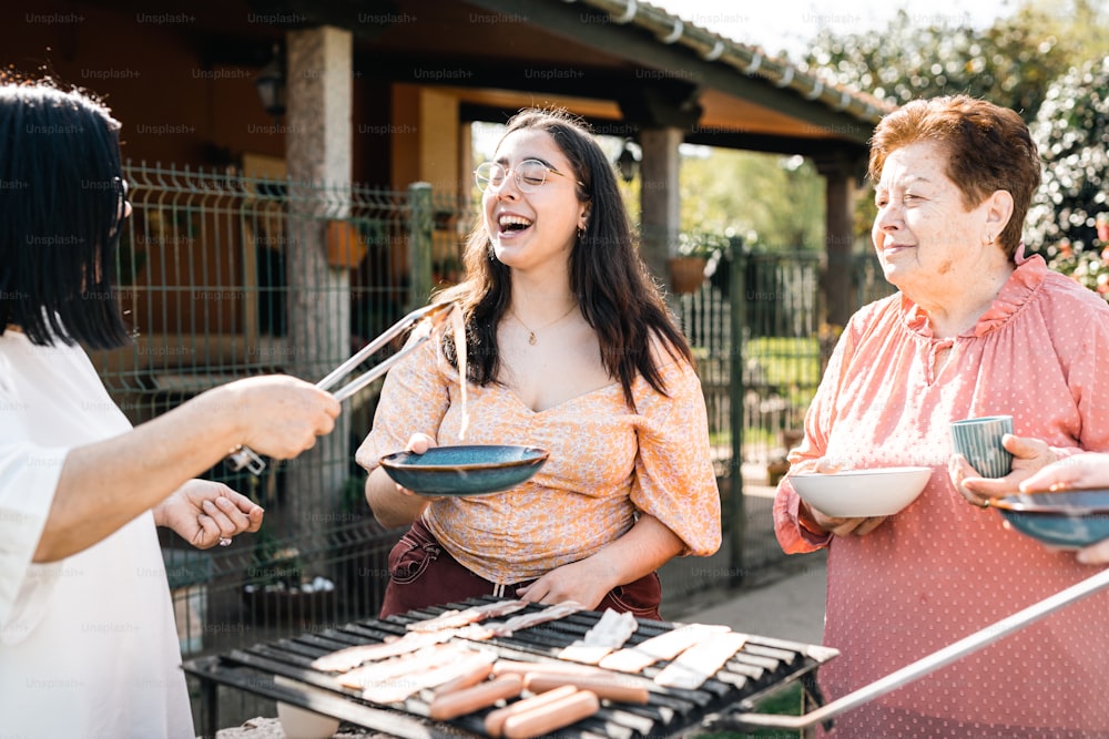 a group of women standing around a grill with food on it