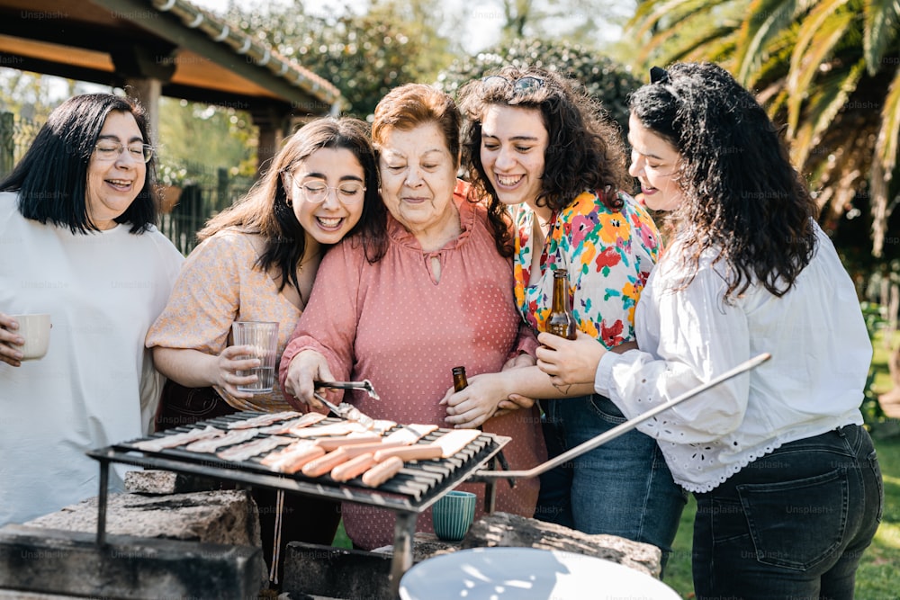 a group of women standing around a bbq grill
