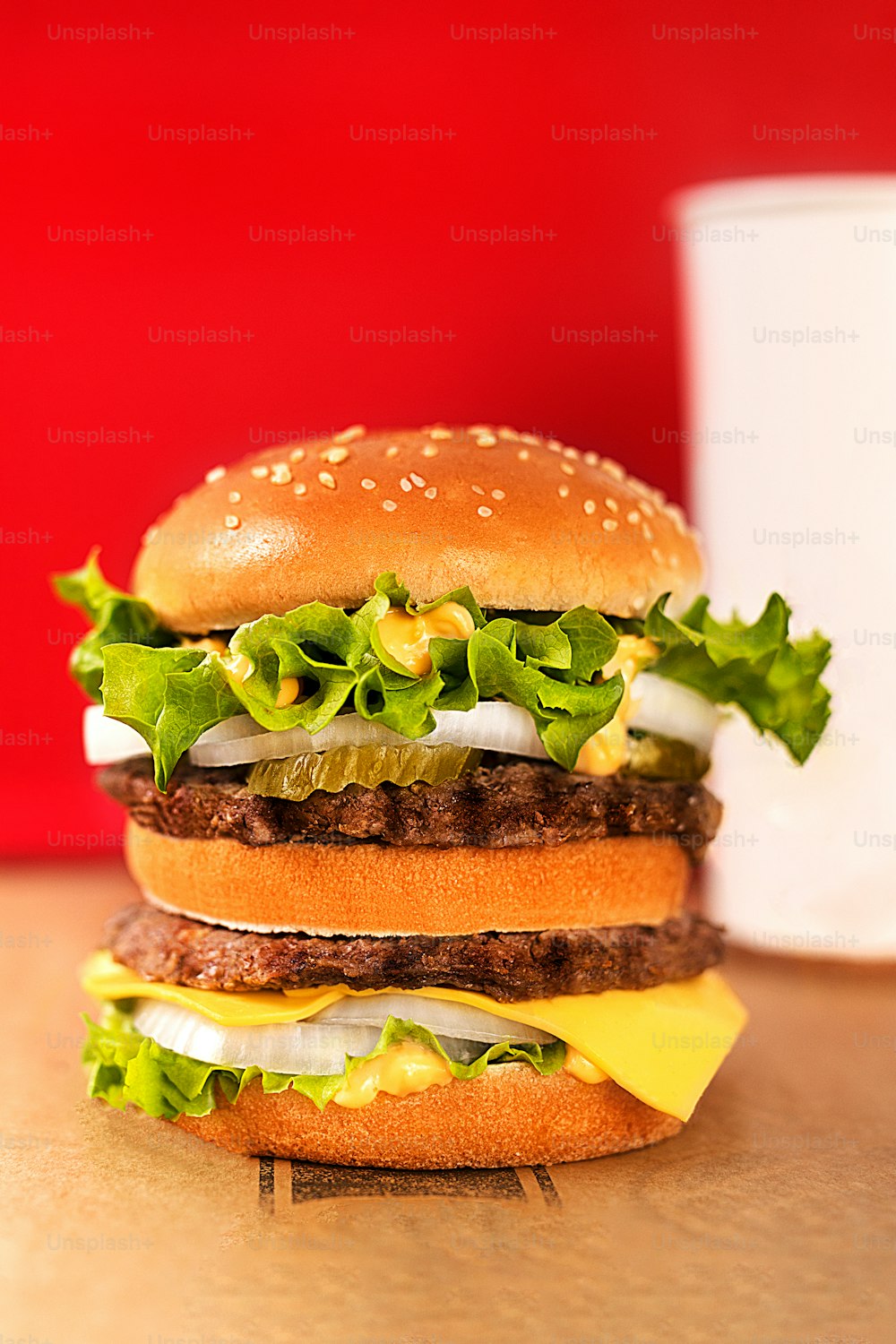una hamburguesa sentada encima de una mesa junto a una taza