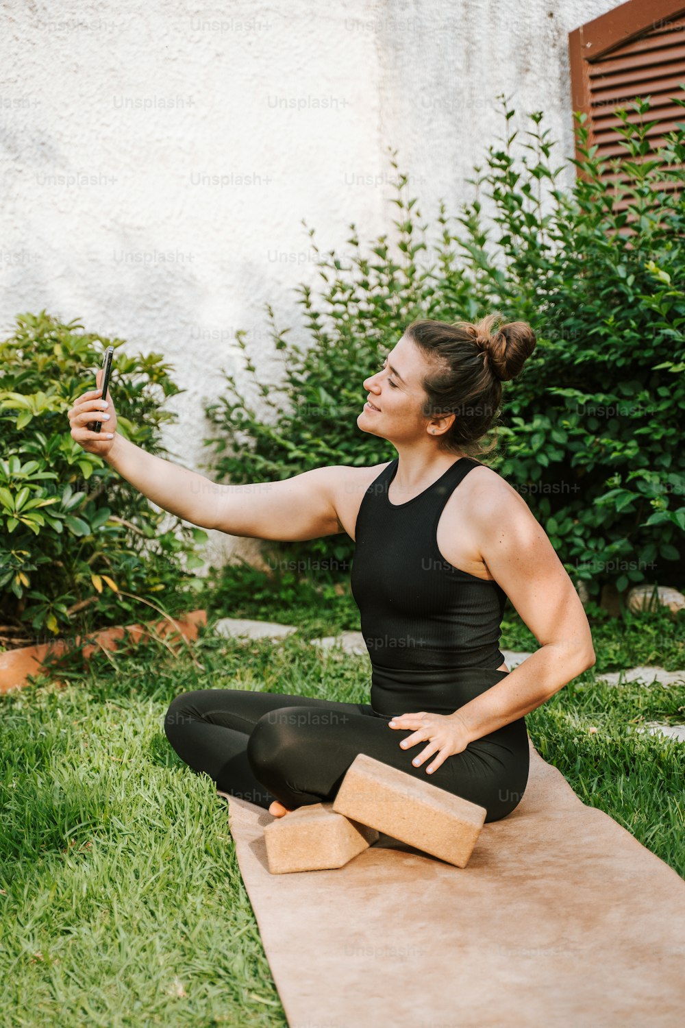 Una mujer sentada en una esterilla de yoga tomándose una selfie