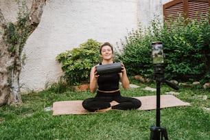 a woman sitting on a yoga mat in the grass