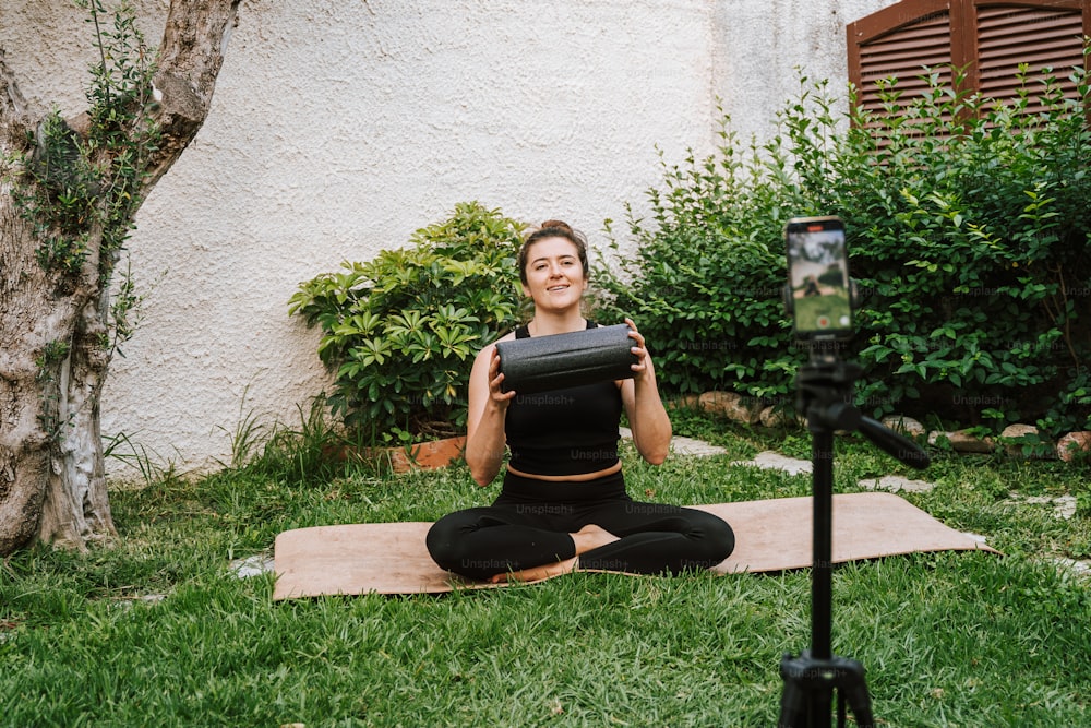 a woman sitting on a yoga mat in the grass