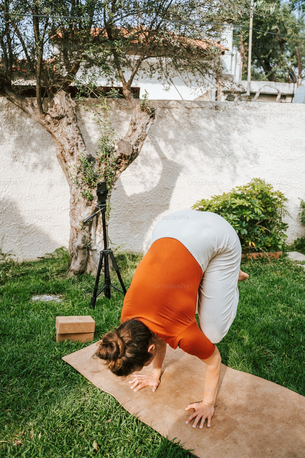 a woman in an orange and white shirt doing a yoga pose