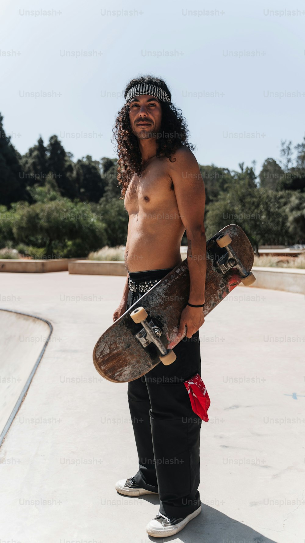 Ein Mann mit langen Haaren, der ein Skateboard hält