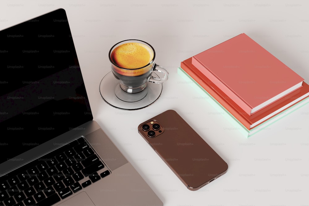 uma xícara de café ao lado de um laptop e um telefone