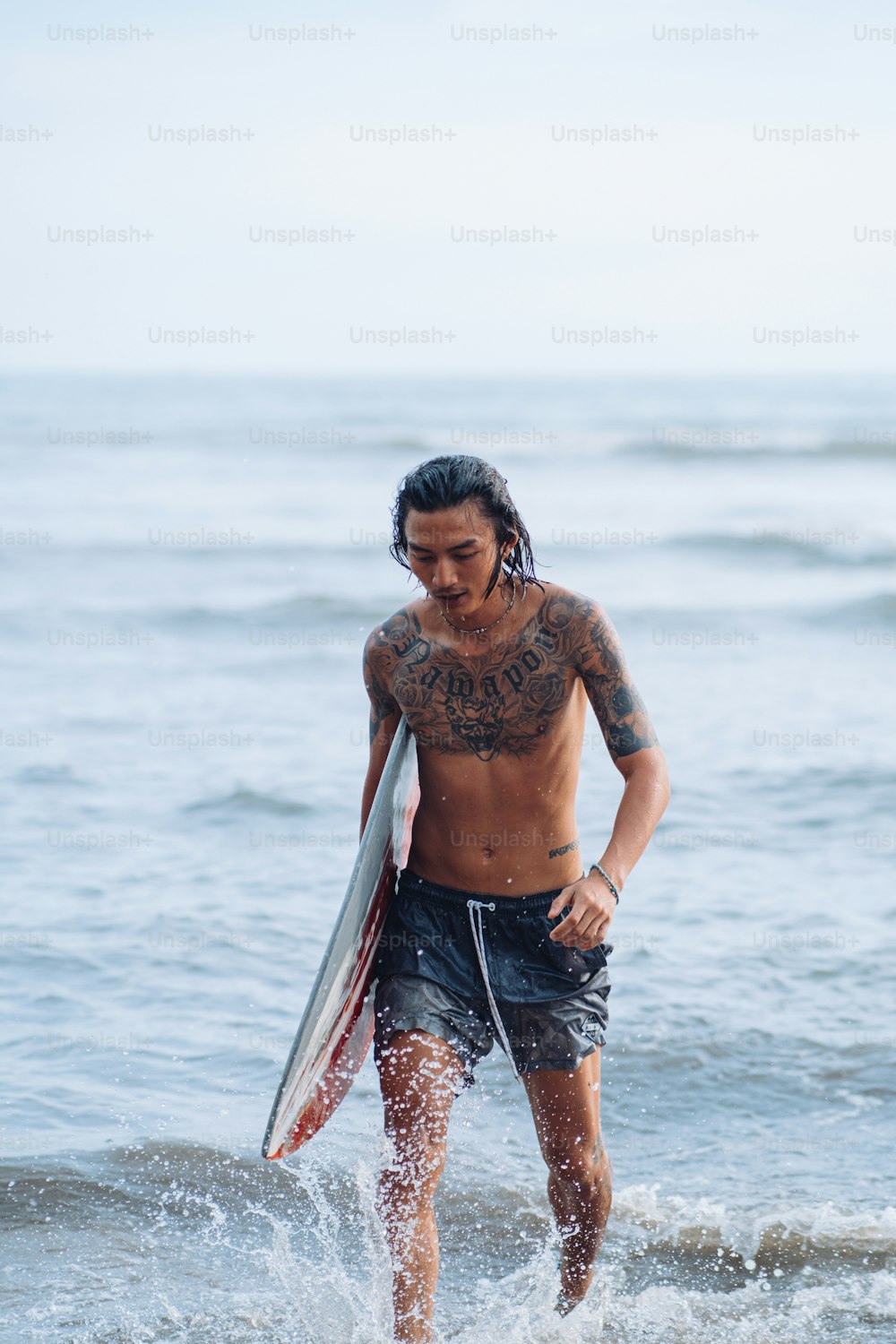 a man walking out of the ocean with a surfboard