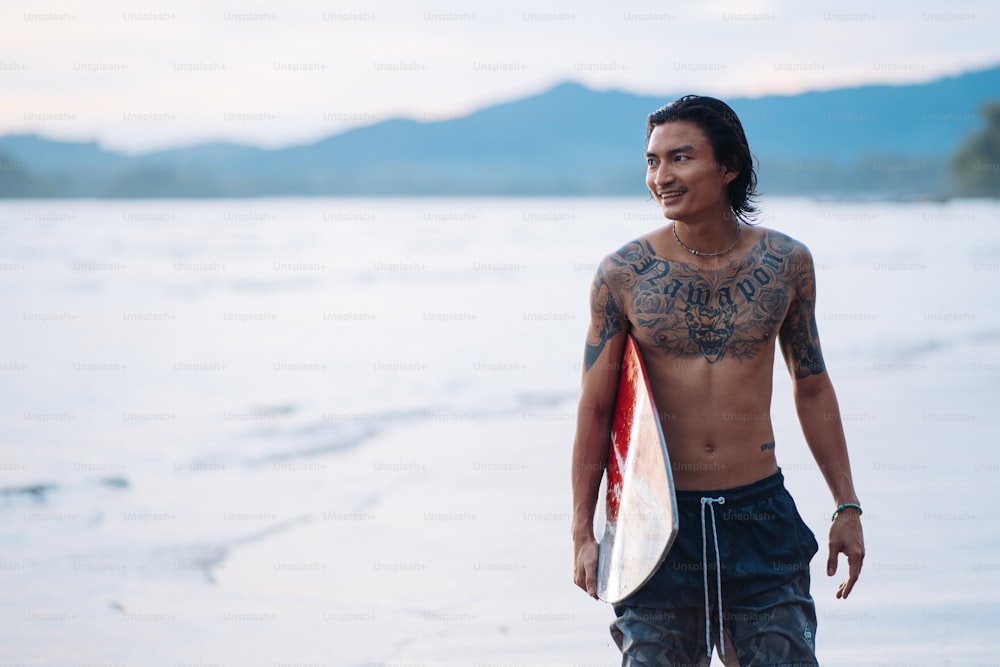 Un homme tenant une planche de surf sur une plage