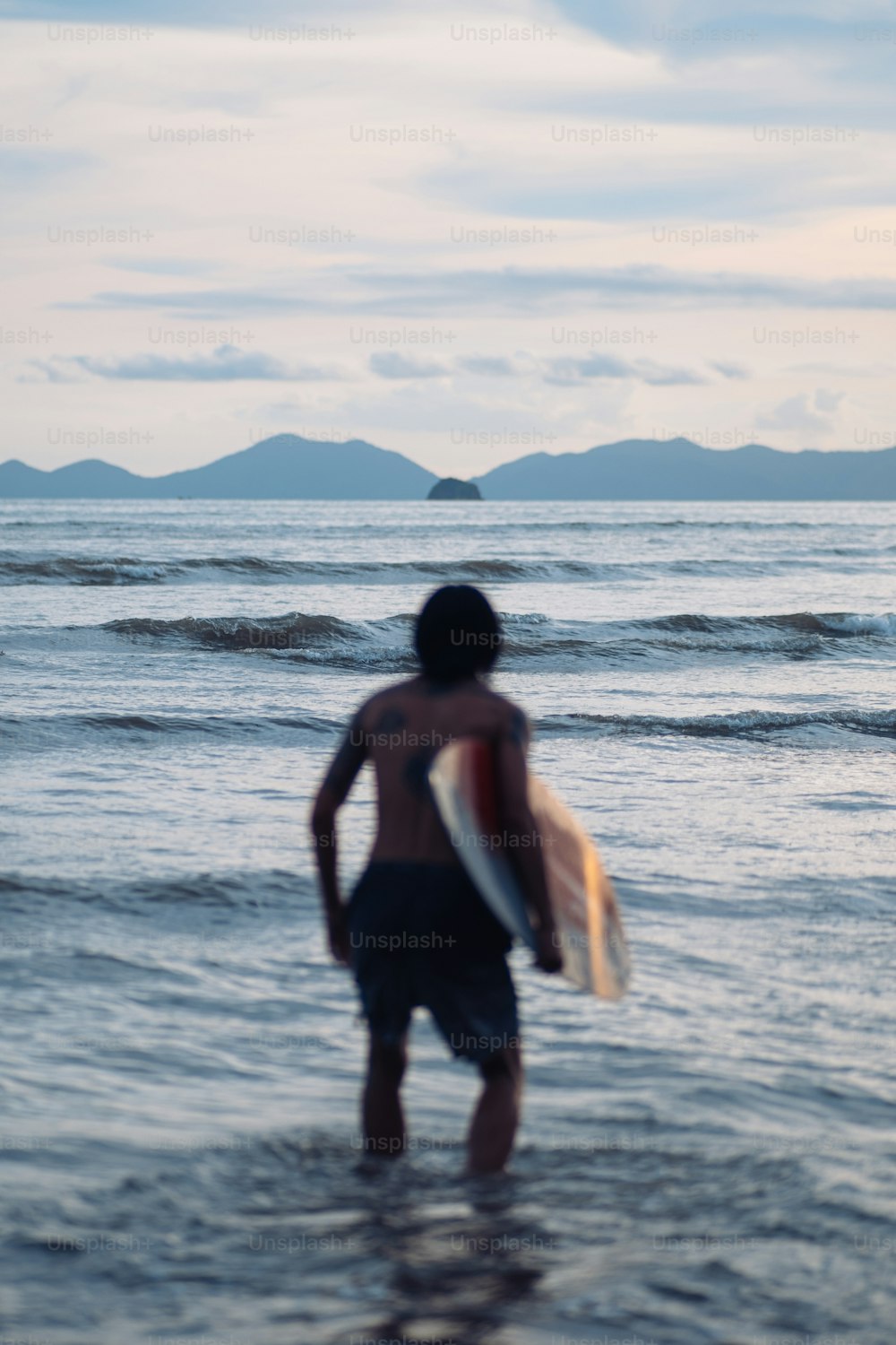 ein mann, der im meer steht und ein surfbrett hält