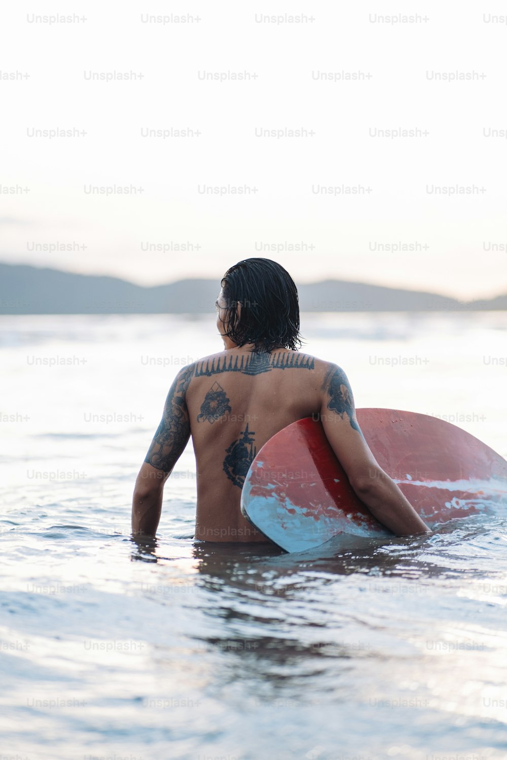 um homem segurando uma prancha de surf na água