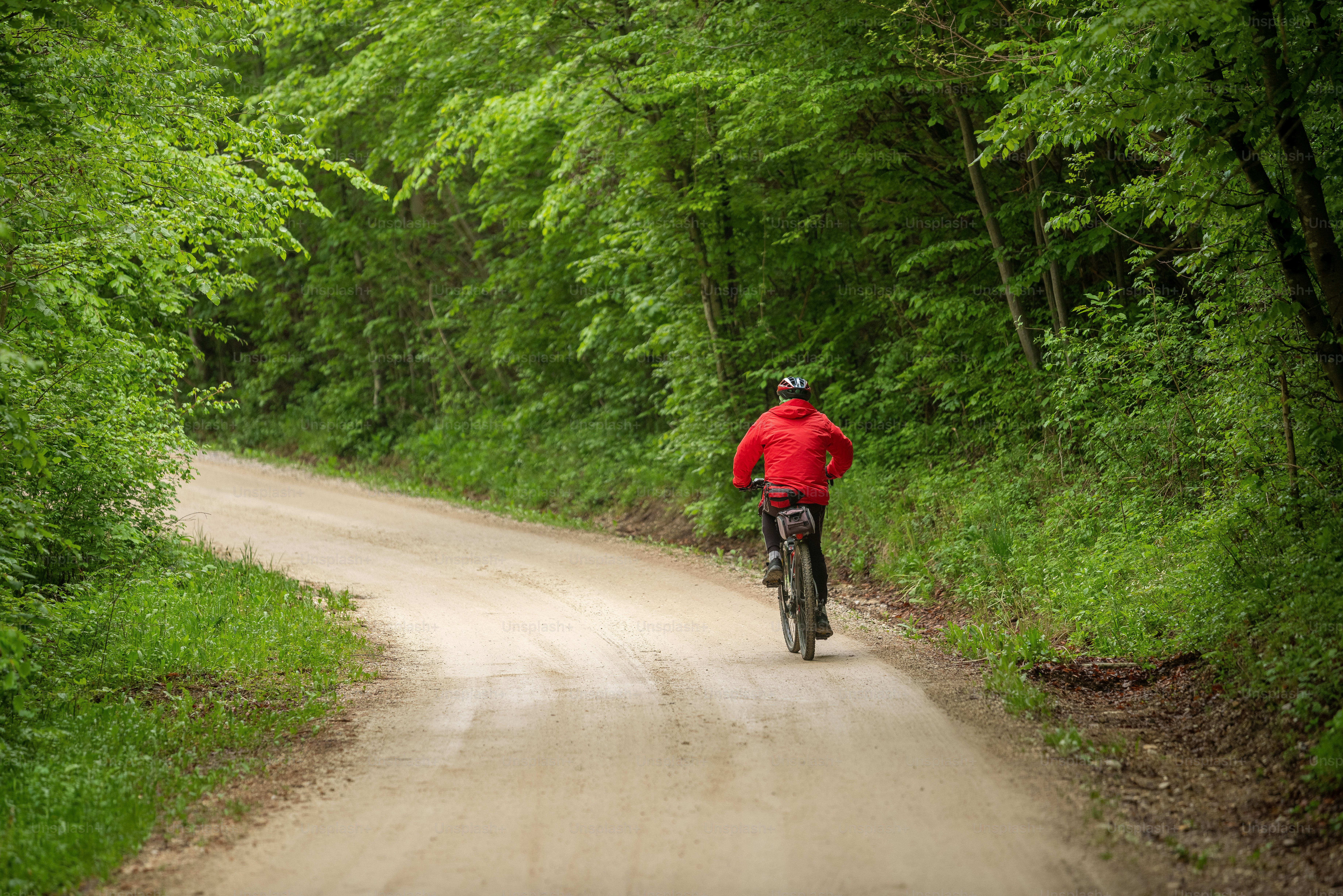 a man riding a bike down a dirt road
