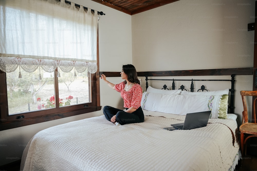 a woman sitting on a bed with a laptop