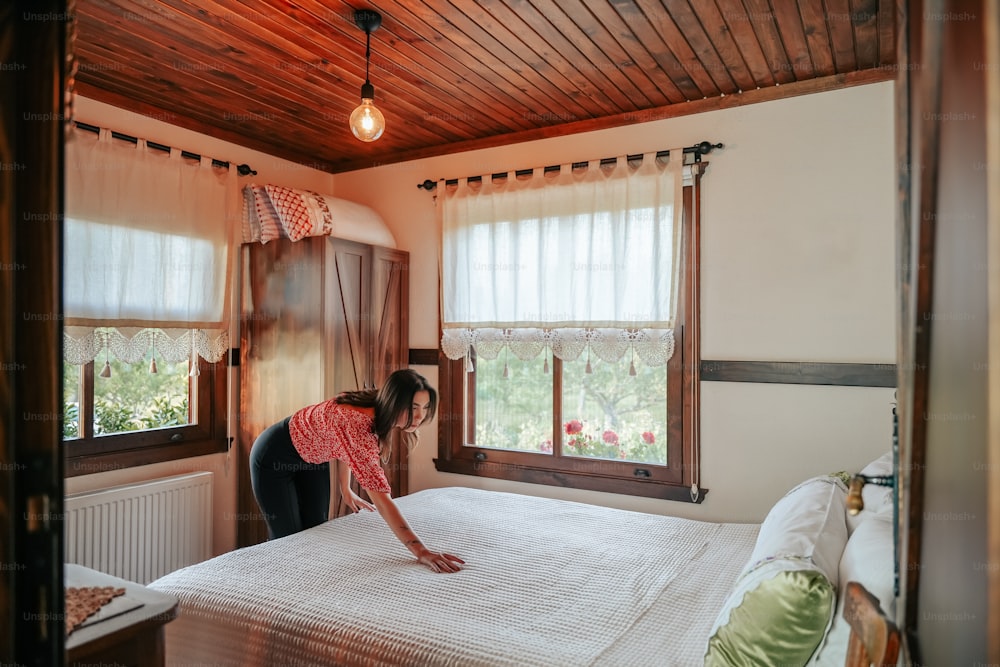 a woman standing on a bed in a bedroom