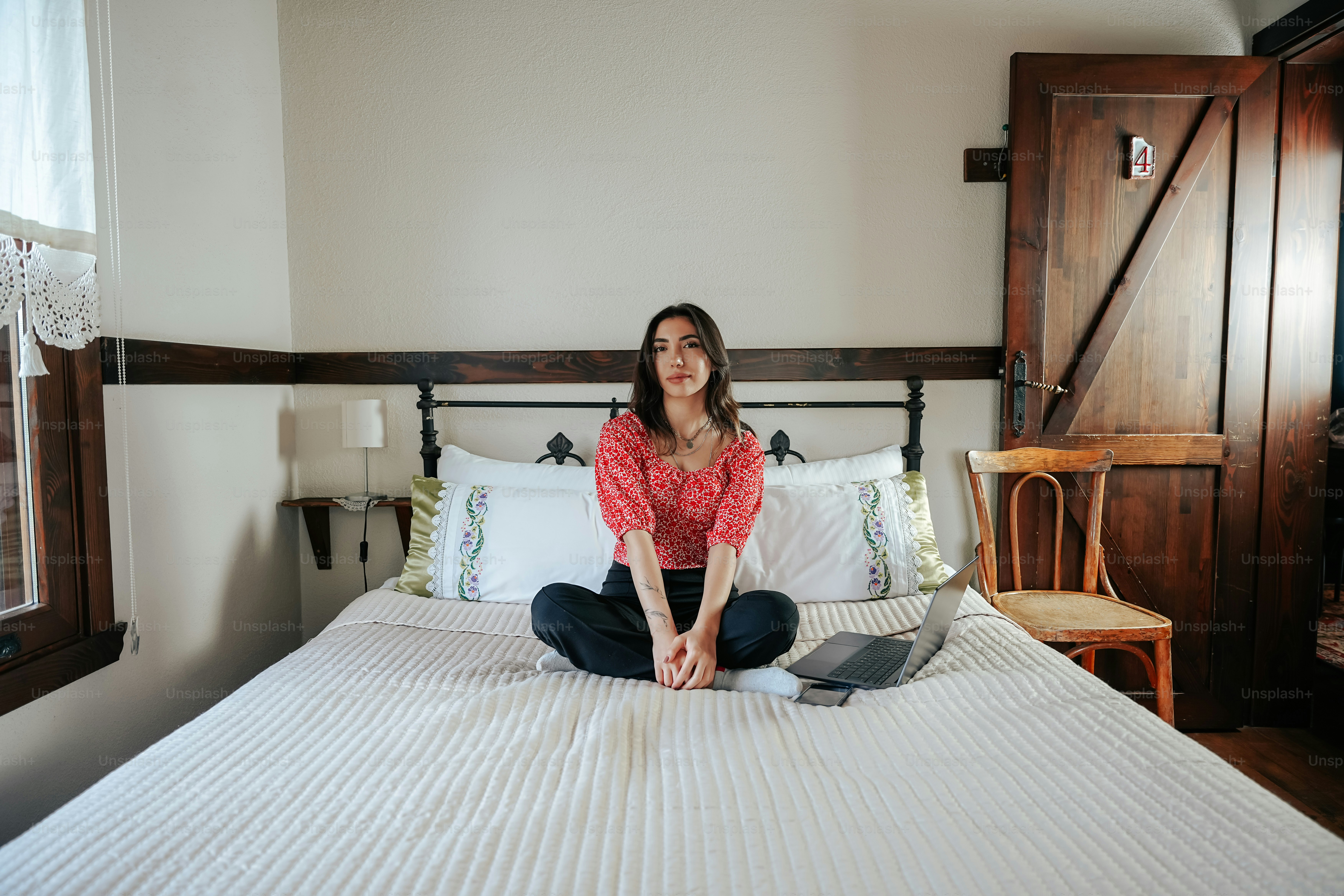 Une femme assise sur un lit avec un ordinateur portable